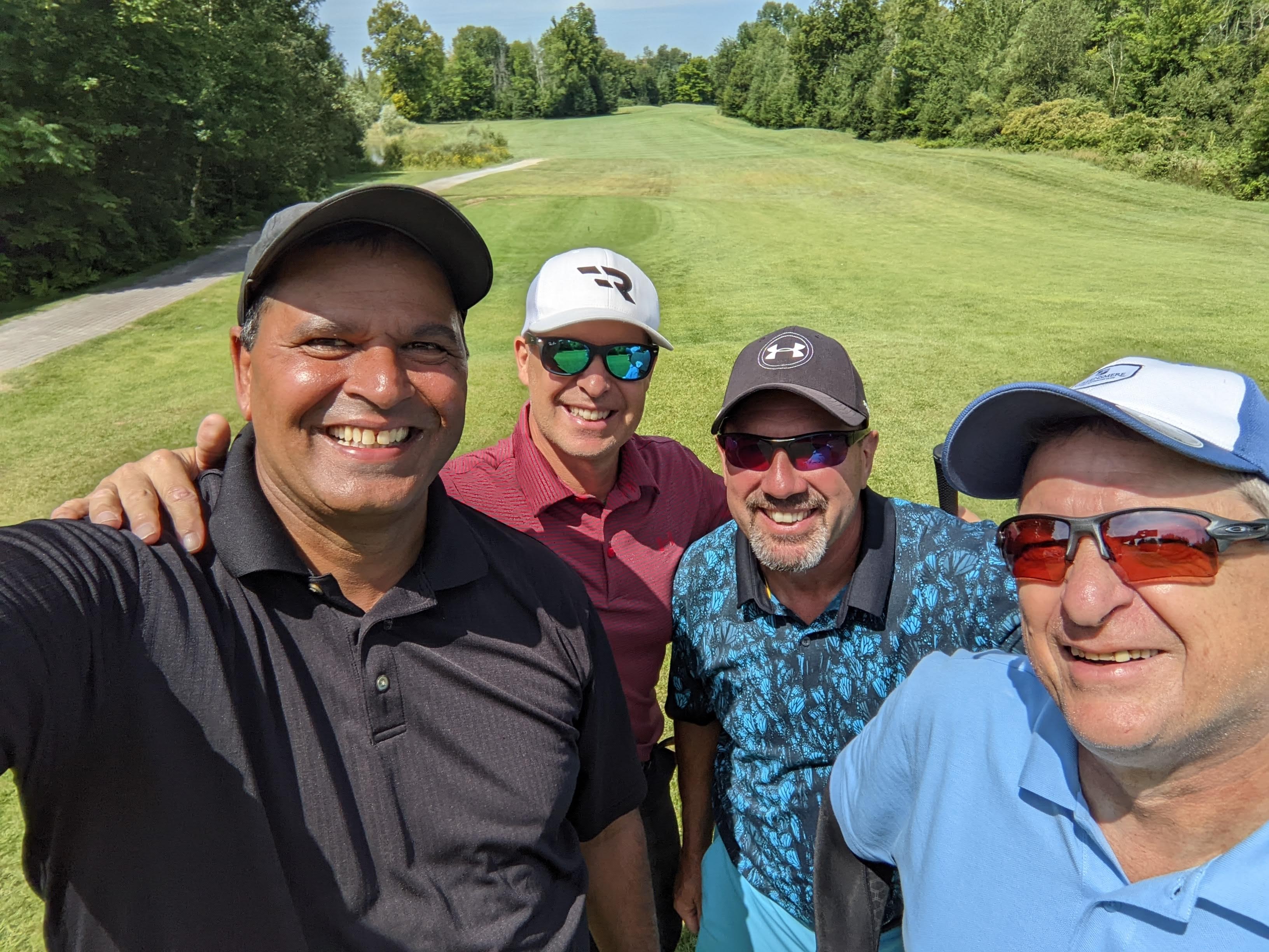 四名男子在高尔夫球场微笑的自拍照